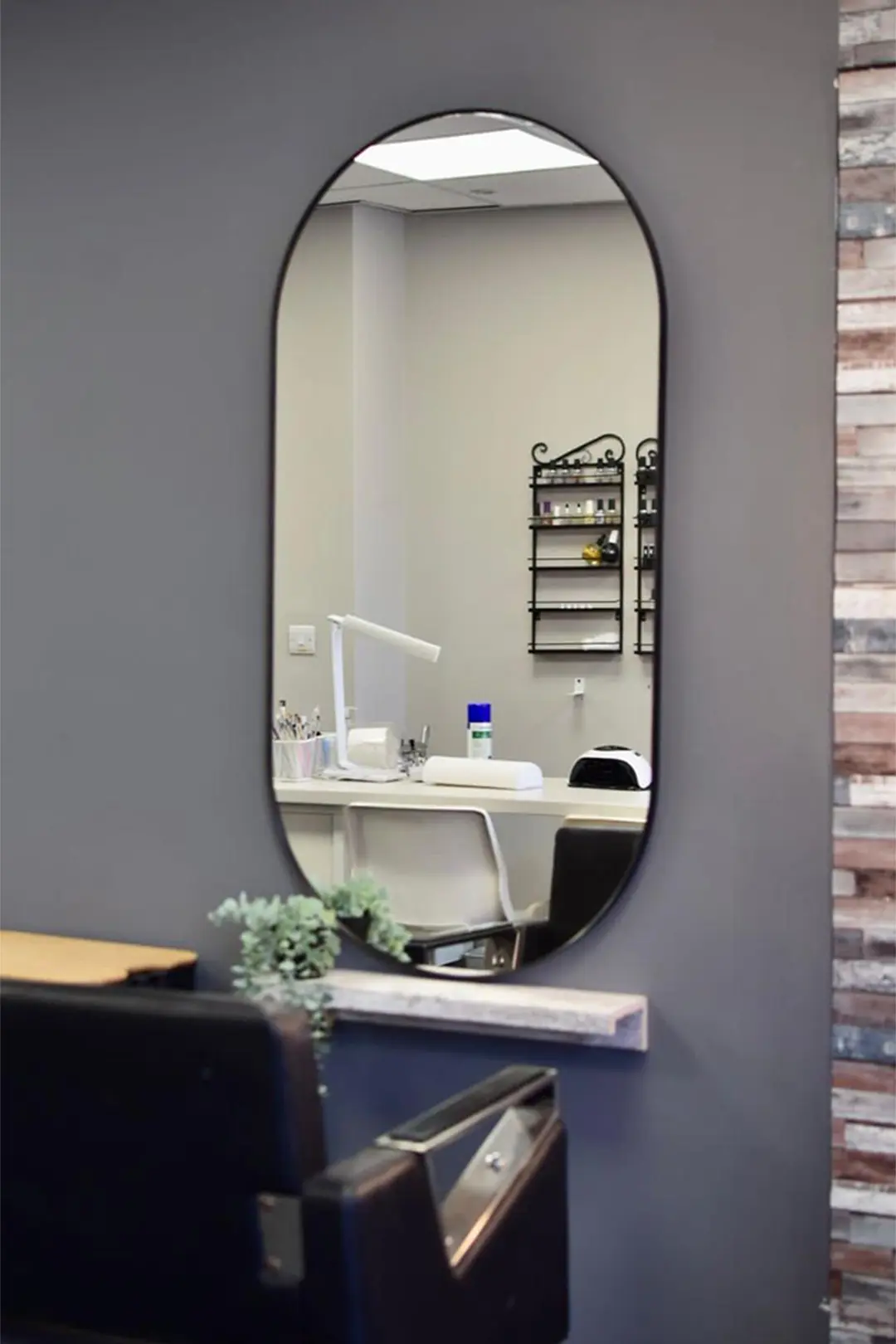 Photo showing hair salon seat with reflection of nail station in the background